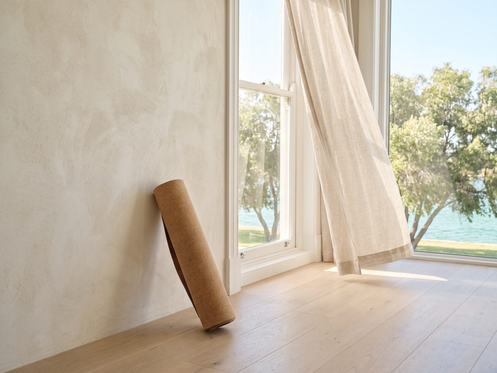 A rolled yoga mat by a window in the early morning light